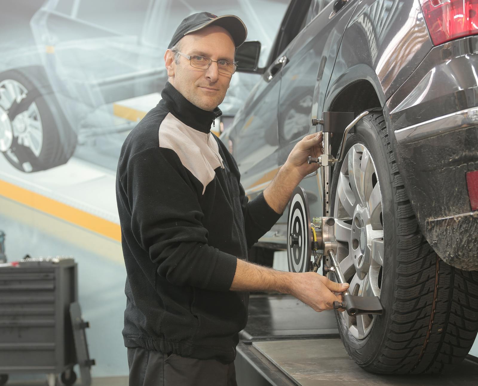 Mechanic performing a wheel alignment with sensor clamp on a wheel