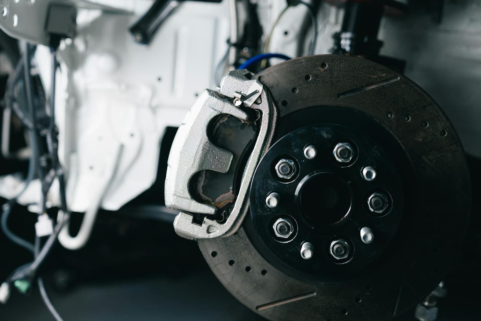 Drilled and slotted brake rotor with caliper